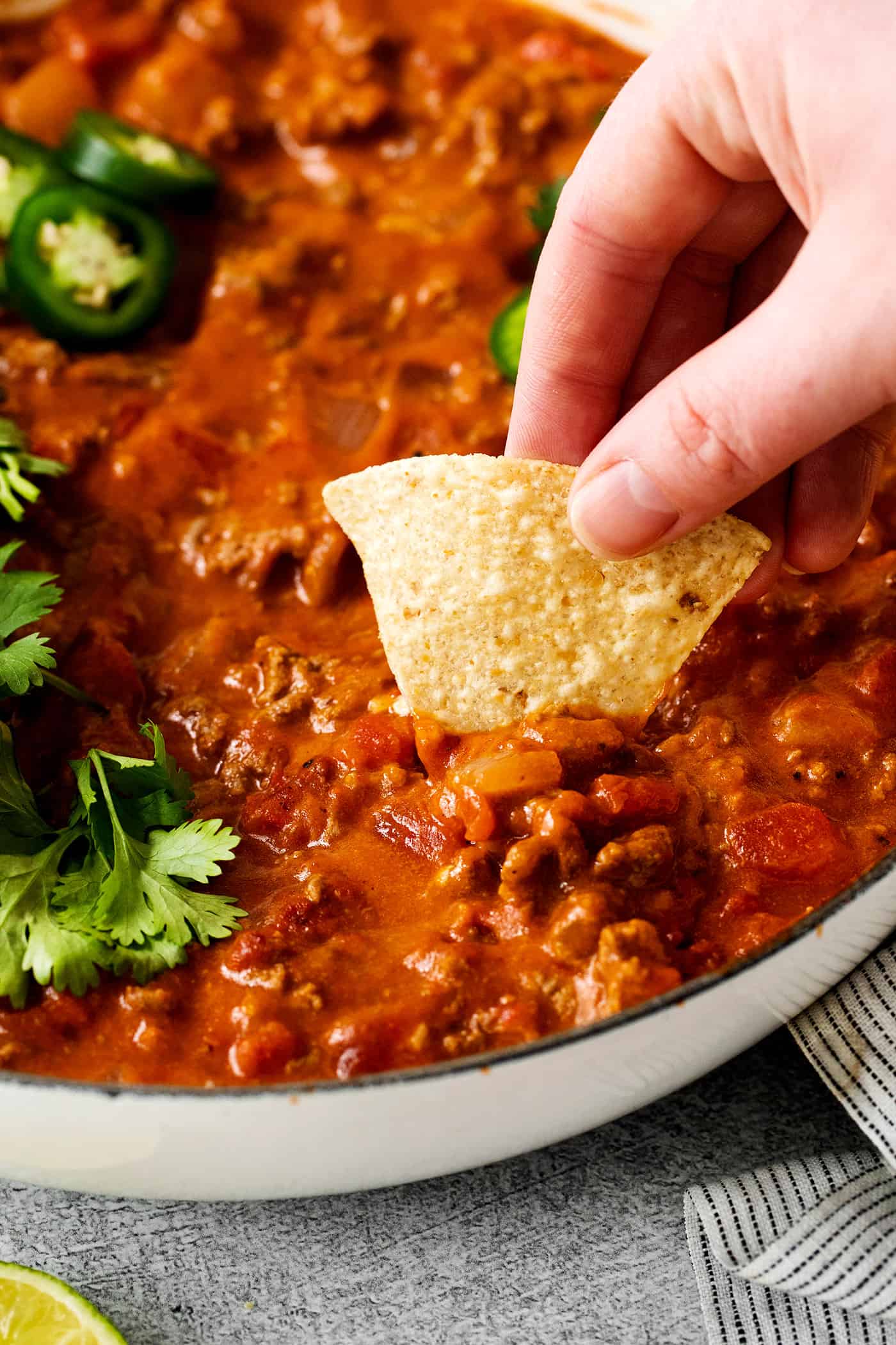 A tortilla chip digging into cheesy taco dip