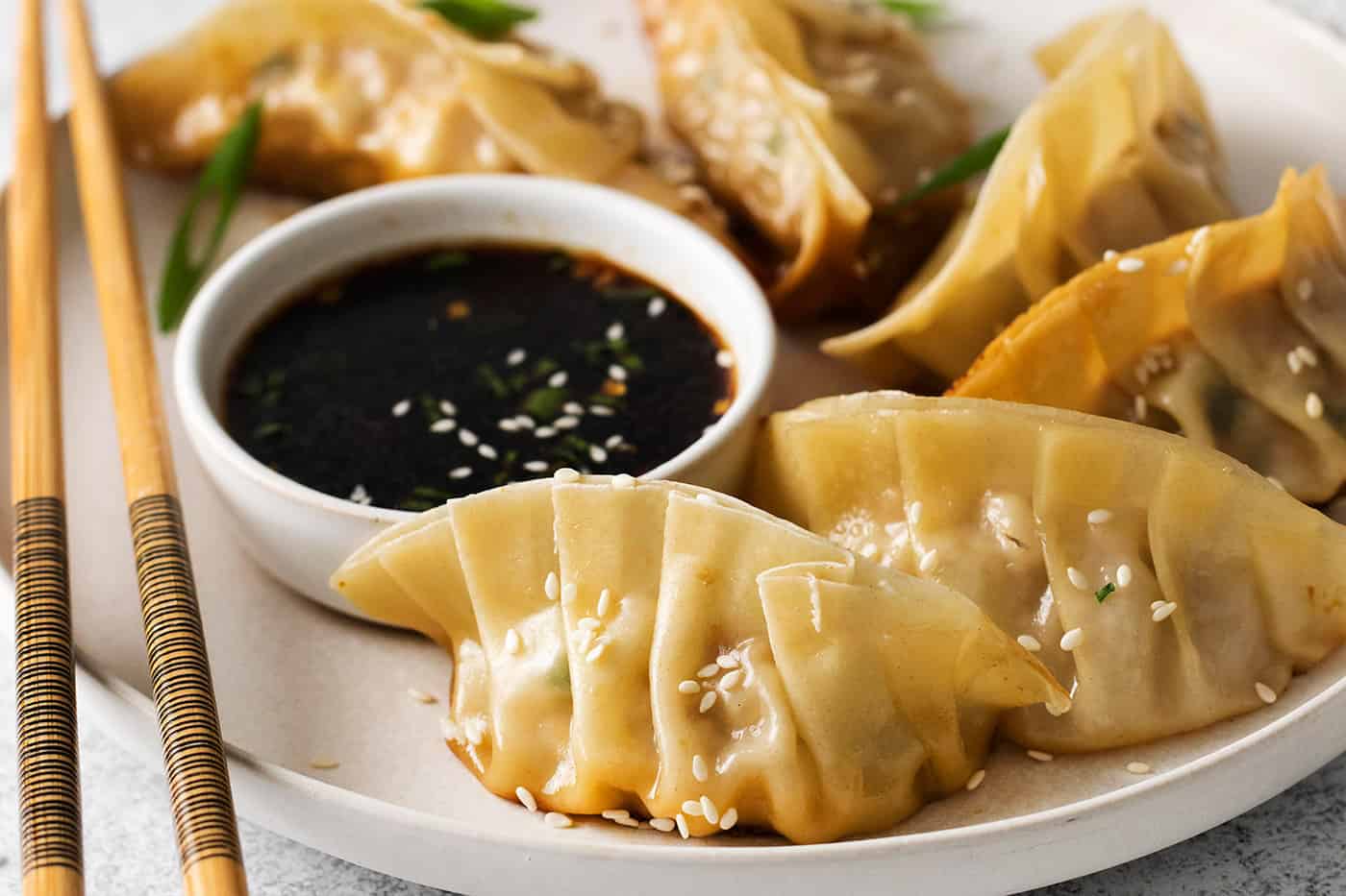 Pork and cabbage potstickers on a plate with dipping sauce