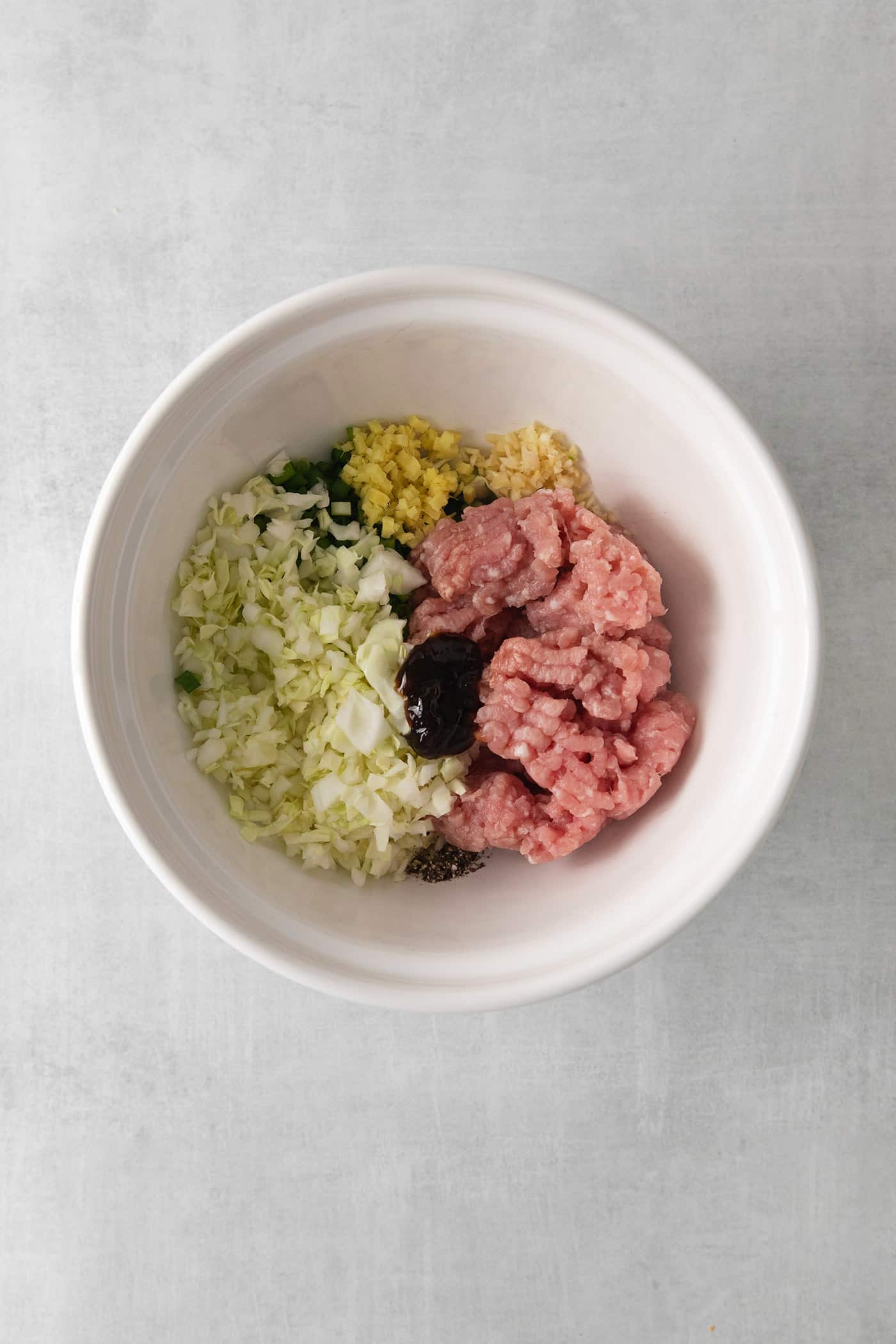 Ground pork, cabbage, and seasoning in a bowl