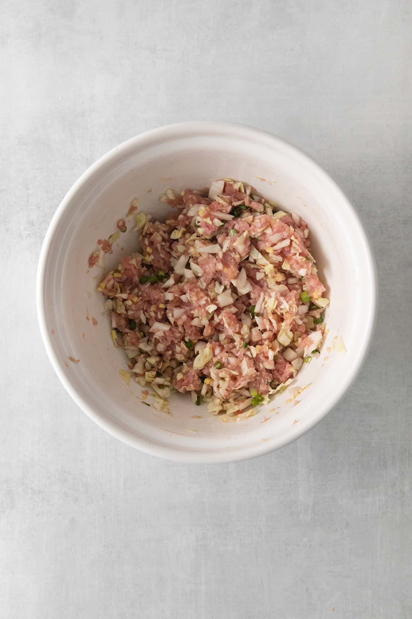 A mixture of ground pork, cabbage, and other ingredients in a bowl