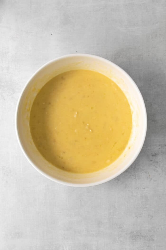 Overhead view of a bowl of mashed bananas with other wet ingredients