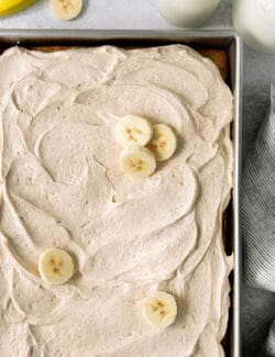 Homemade banana cake topped with cream cheese frosting and banana slices