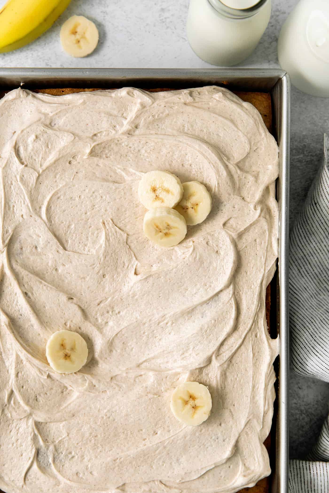 Homemade banana cake topped with cream cheese frosting and banana slices