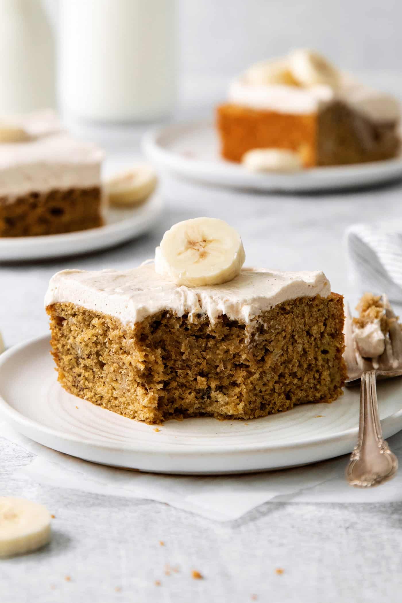 A slice of homemade banana cake on a plate with a bite missing