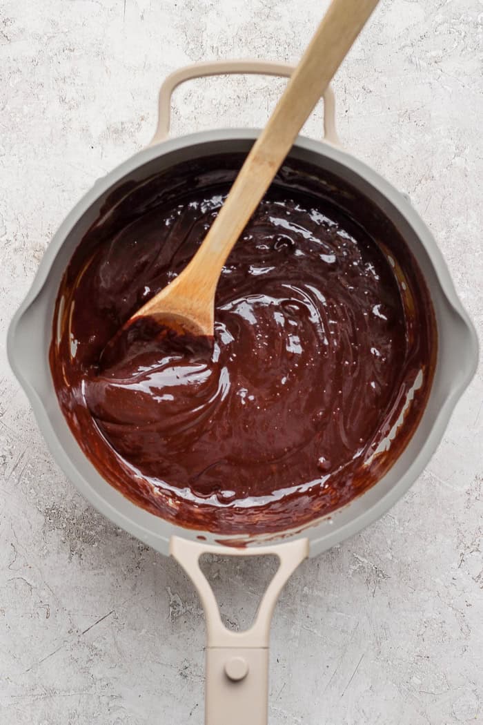 Stirring melted chocolate and cream in pan