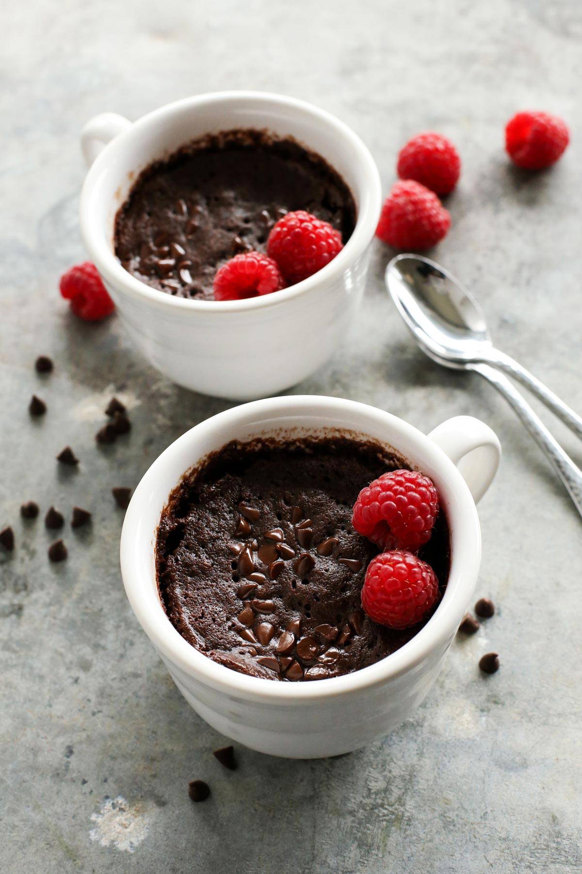 two chocolate mug cakes and fresh raspberries