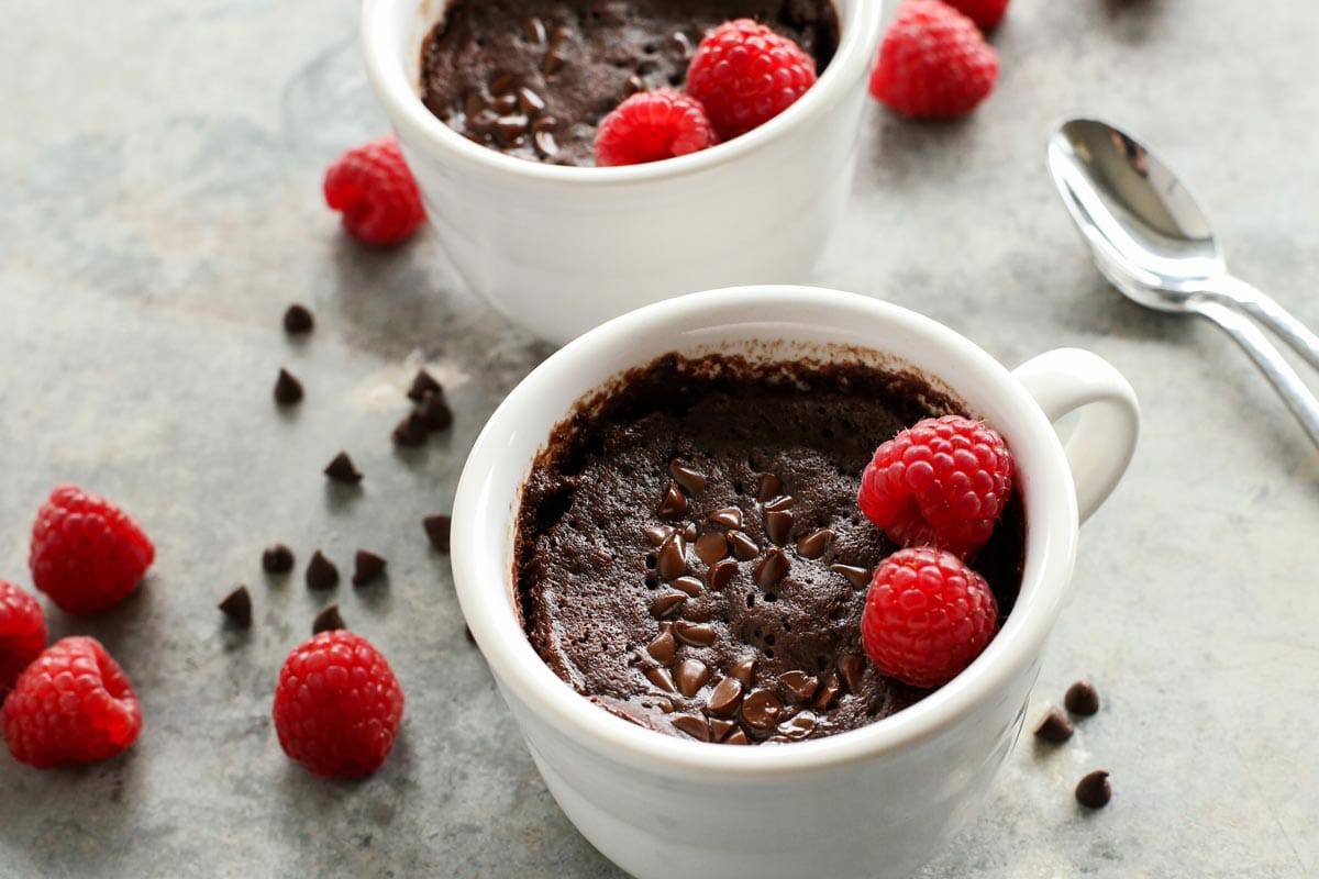 two mugs of chocolate cake and fresh raspberries