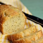 A Loaf of Lemon Poppy Seed Bread Being Sliced into Servings