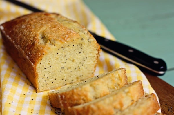 A Loaf of Lemon Poppy Seed Bread Being Sliced into Servings