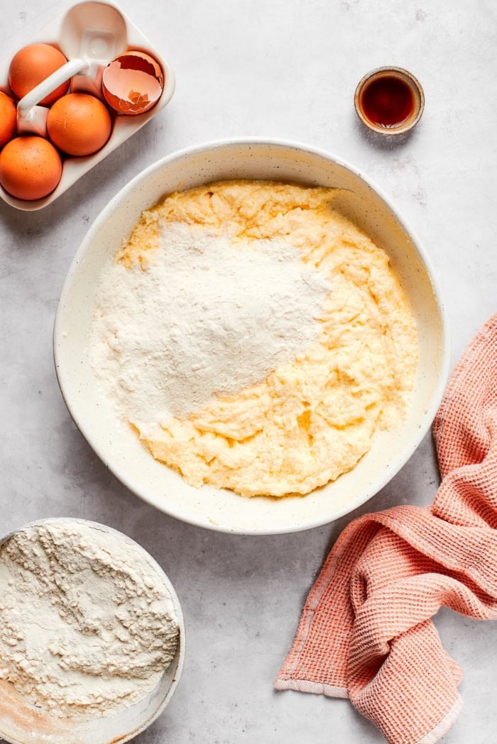 Flour added to bowl of wet ingredients for cream cheese pound cake.