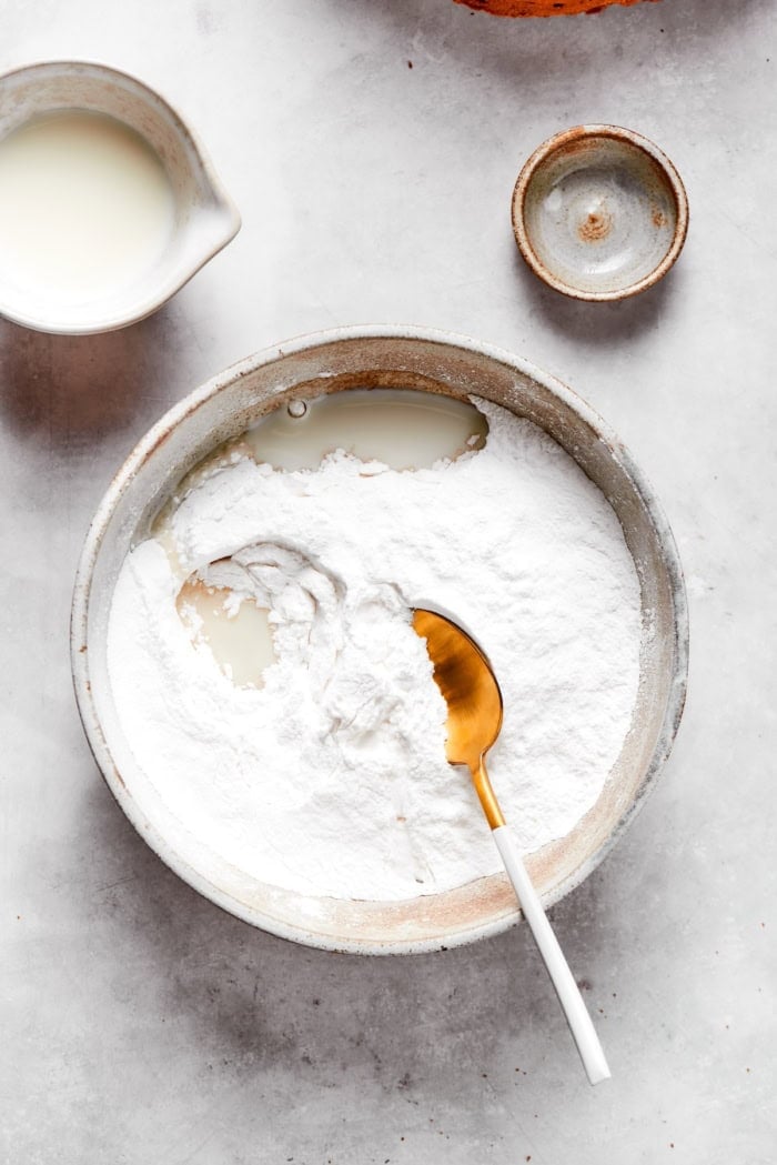 Spoon in bowl with milk and powdered sugar.