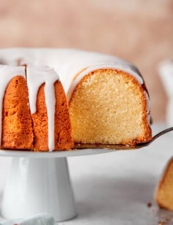 Lifting slice of cream cheese pound cake from cake stand.