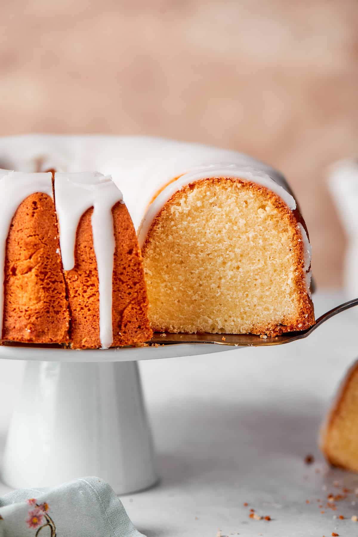 Lifting slice of cream cheese pound cake from cake stand.