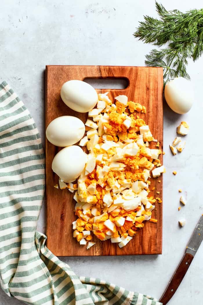 Chopped eggs on wooden cutting board.