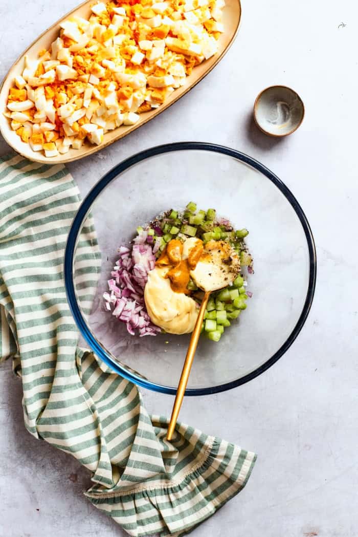 Ingredients for egg salad dressing in bowl with spoon.