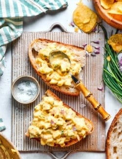 Spoon set on slice of bread topped with creamy egg salad.