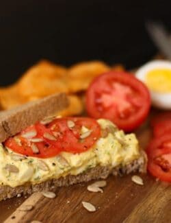 A piece of bread topped with herby egg salad and tomatoes