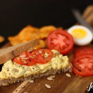 A piece of bread topped with herby egg salad and tomatoes