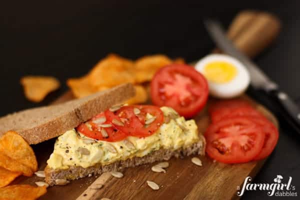 a piece of bread topped with herby egg salad and tomatoes