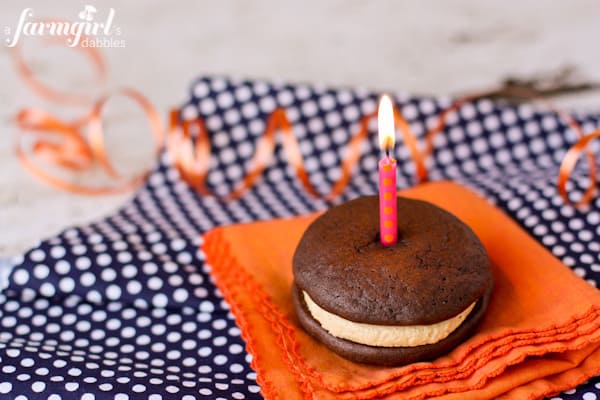 A whoopie pie with a pink candle on top.