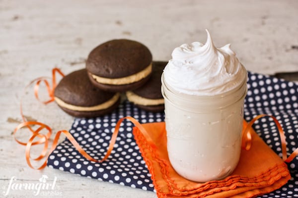 A jar of marshmallow cream next to a stack of whoopie pies.