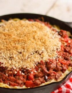 a skillet pan of Spaghetti Hotdish topped with Garlic Bread Crumbs