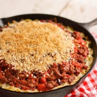 a skillet pan of Spaghetti Hotdish topped with Garlic Bread Crumbs