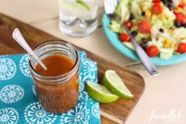 a jar of Honey and Chipotle Vinaigrette and a plate of fresh salad