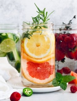 Large jar of spa water with lemon, orange, grapefruit, and rosemary