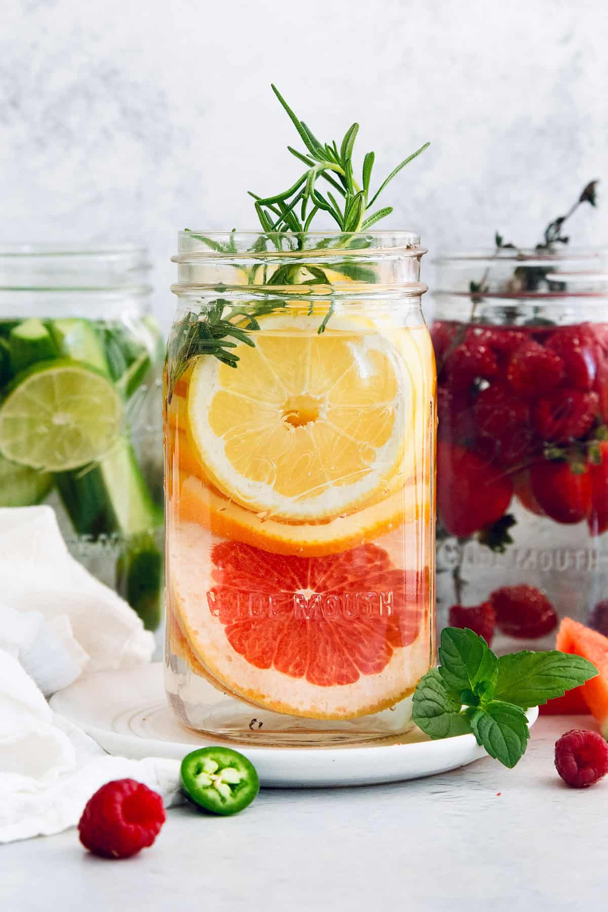 Large jar of spa water with lemon, orange, grapefruit, and rosemary