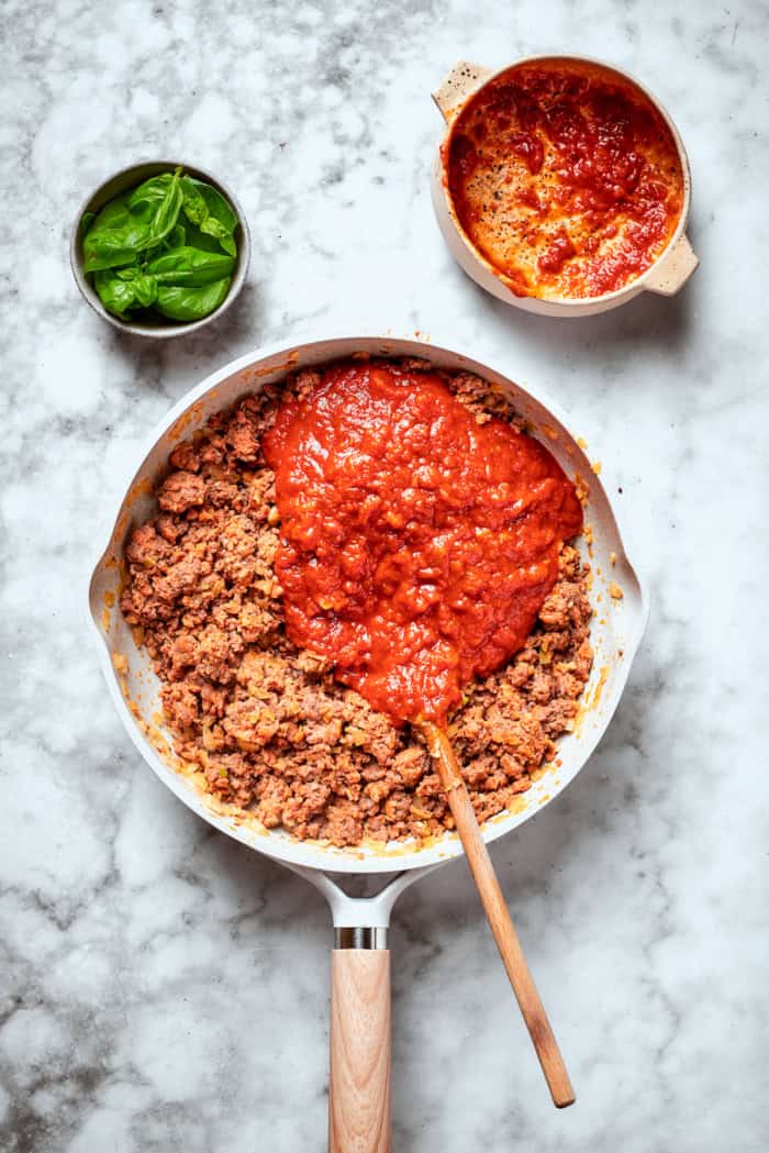 Overhead view of marinara added to meat in skillet