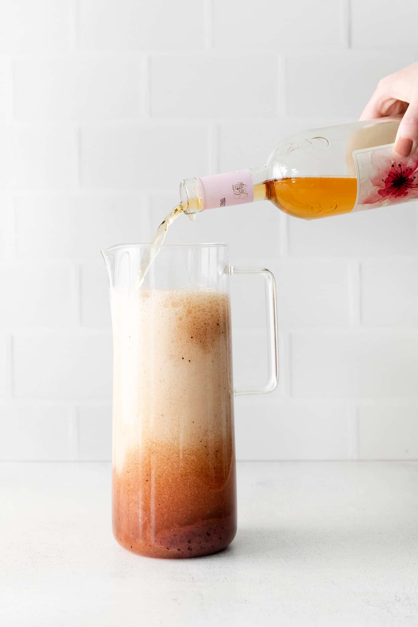 A pitcher being topped with a bottle of fruity rose