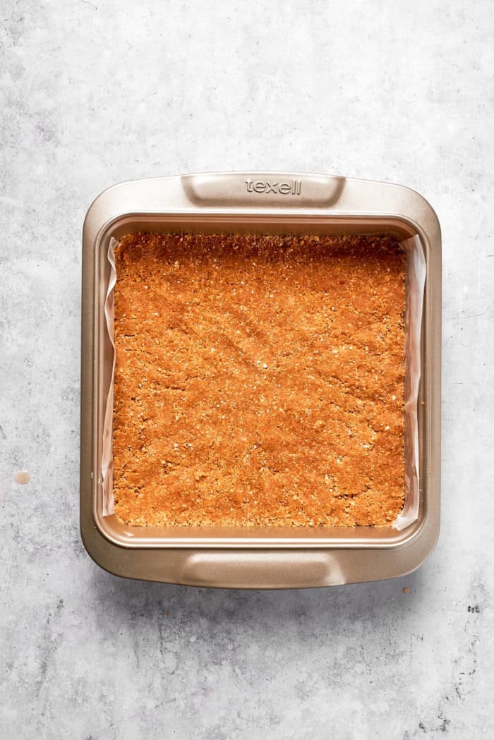 Overhead view of graham cracker crust in square pan