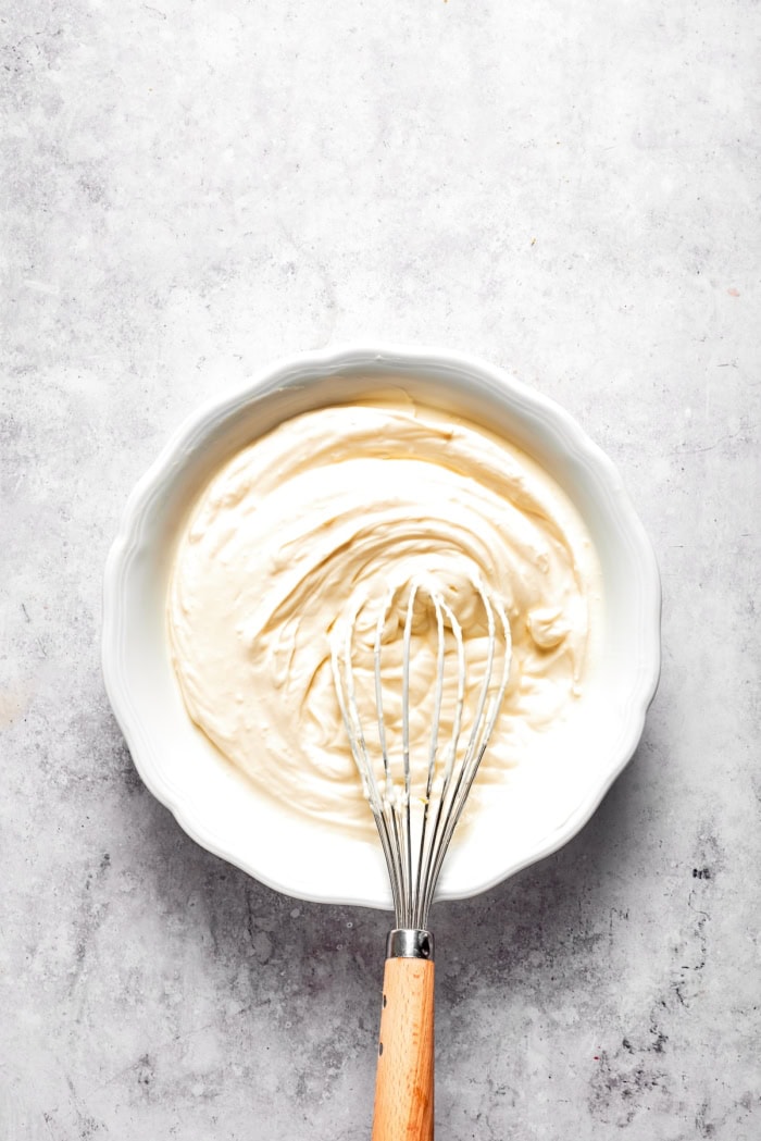 Lemon cheesecake filling in bowl with whisk