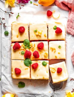 Overhead view of sliced lemon cheesecake bars with raspberries