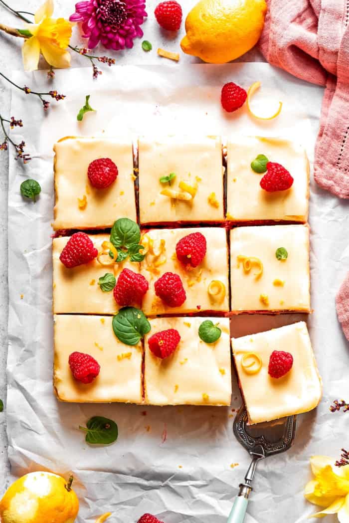 Overhead view of sliced lemon cheesecake bars with raspberries