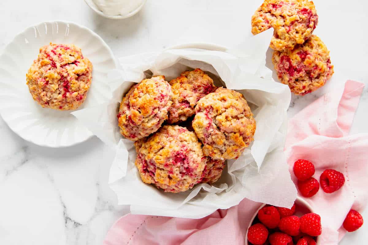 Overhead view of a basket of raspberry drop scones and one on a plate