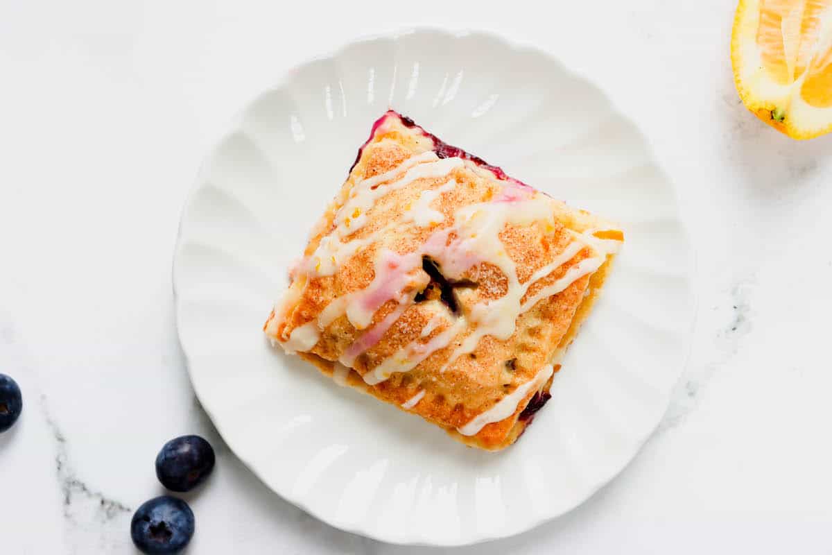 Overhead view of a perfectly baked blueberry hand pie on a white plate
