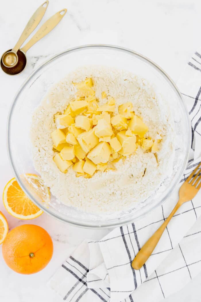 Cold cubed butter added to dry ingredients in a bowl.