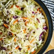 coleslaw dressing on shredded cabbage in a pottery bowl