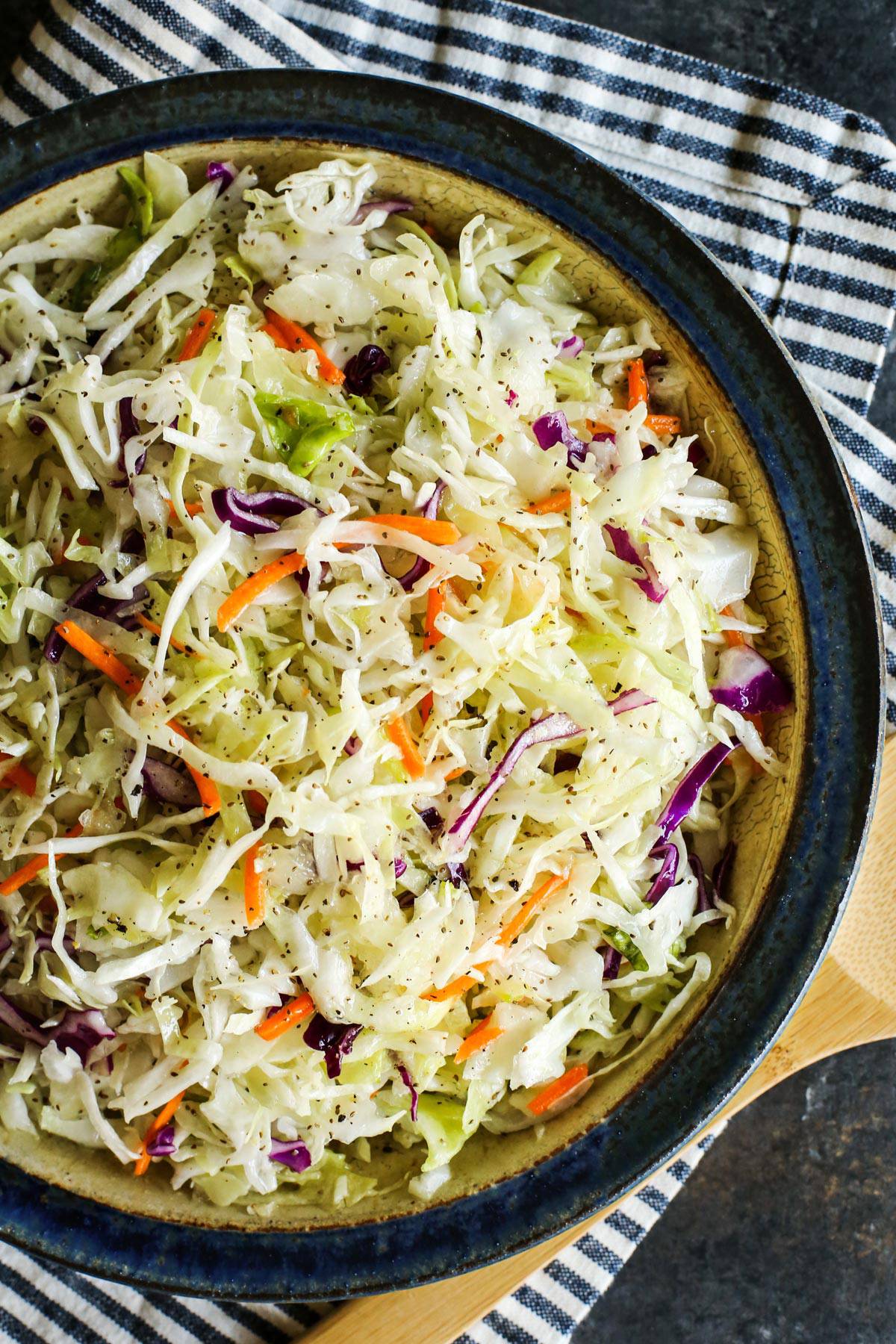 coleslaw dressing on shredded cabbage in a pottery bowl