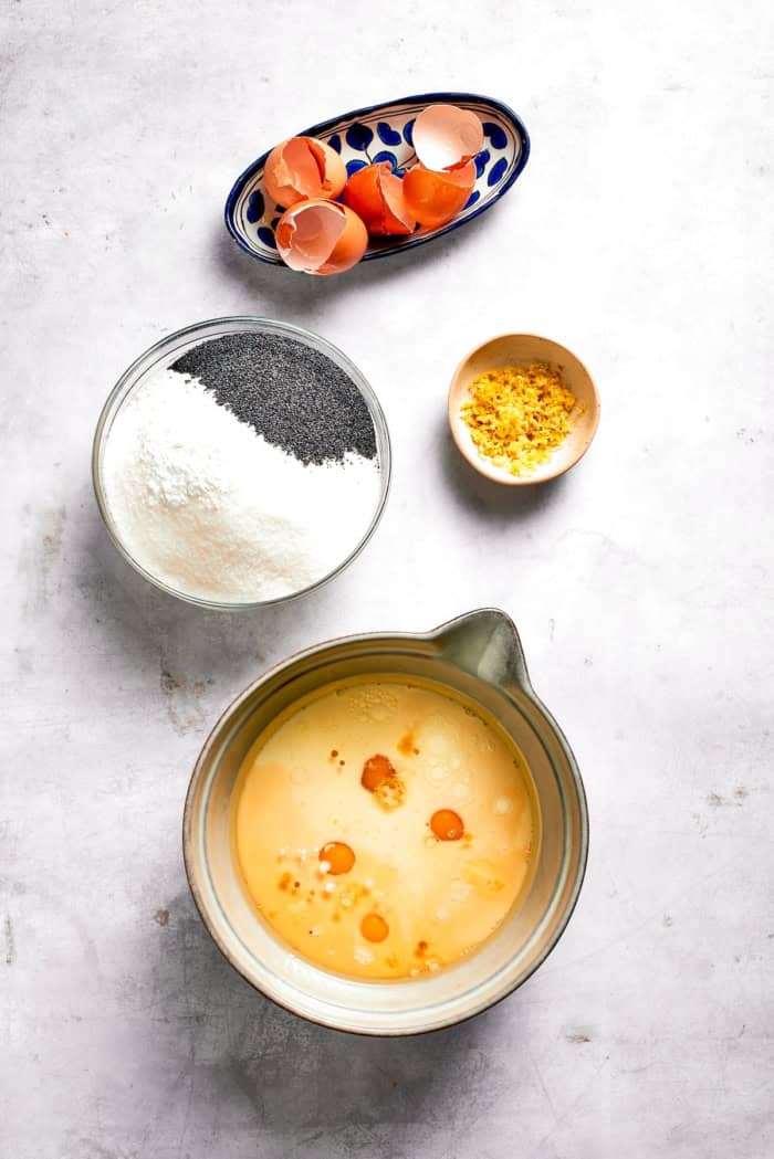 Bowls of wet ingredients, egg shells, dry ingredients, and lemon zest.