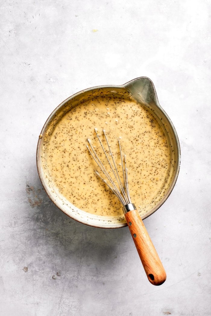 Bowl of batter for almond lemon poppy seed bread with whisk.