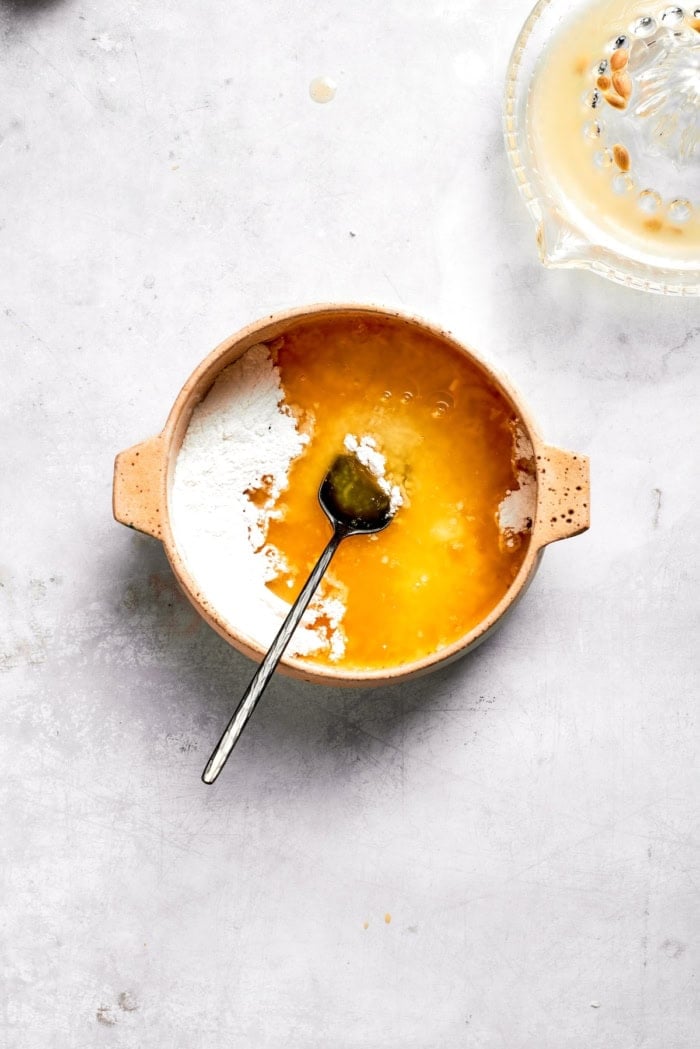 Ingredients for lemon glaze in bowl with spoon.