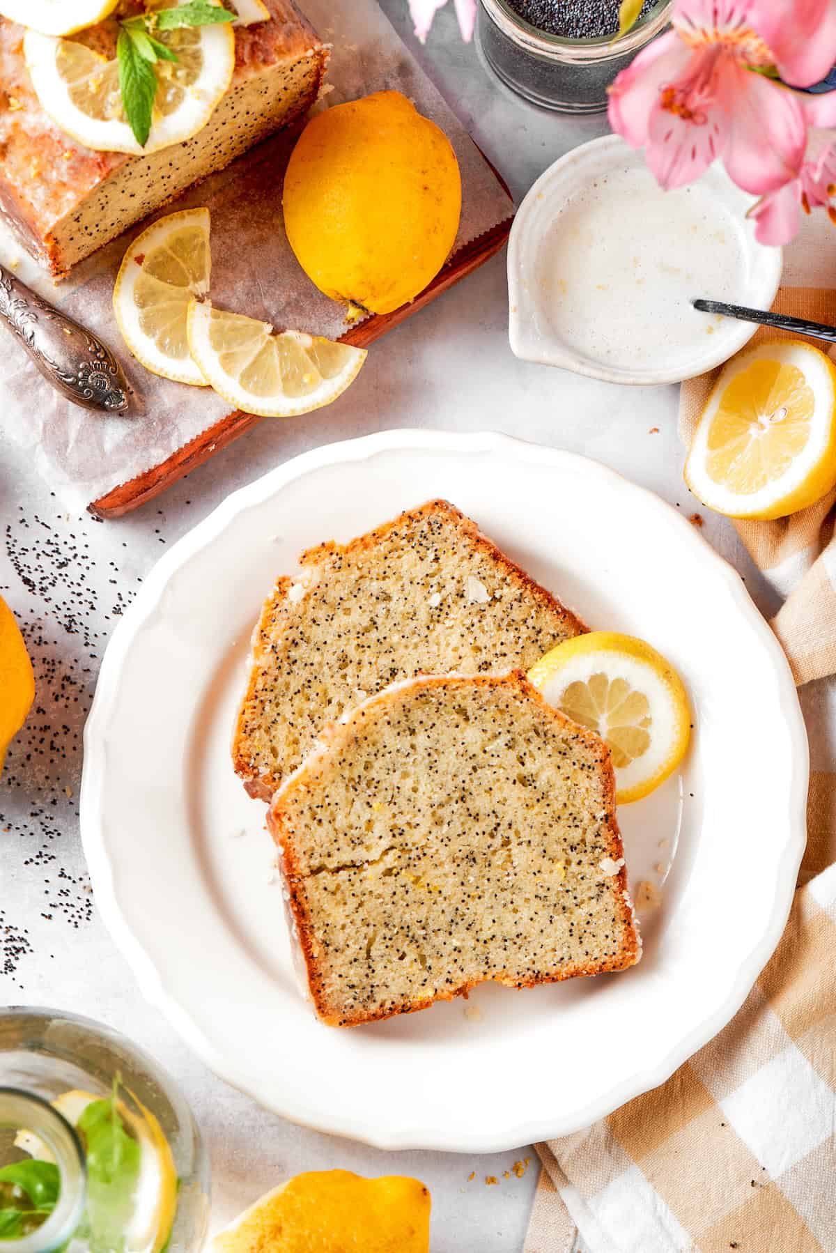 Two slices of almond lemon poppy seed bread on plate with lemon slice.
