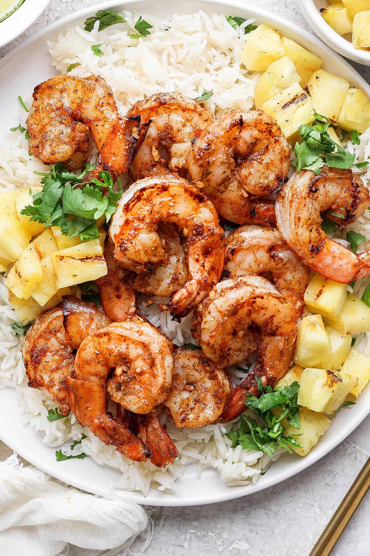 Overhead view of grilled jerk shrimp on plate with cilantro lime rice and pineapple