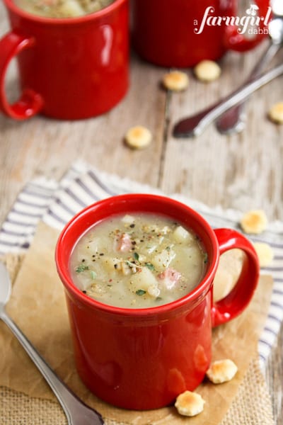 three red mugs of Clam Chowder with oyster crackers