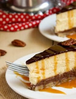 two slices of Turtle Pecan Cluster Cheesecake drizzled with caramel