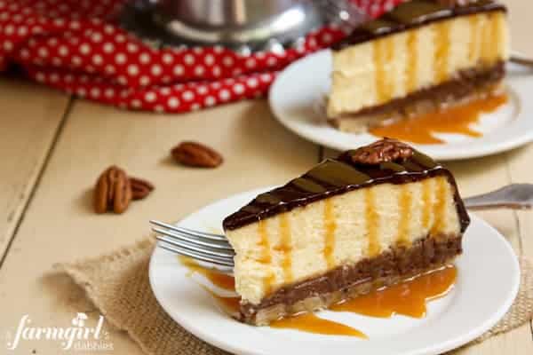 two slices of Turtle Pecan Cluster Cheesecake drizzled with caramel