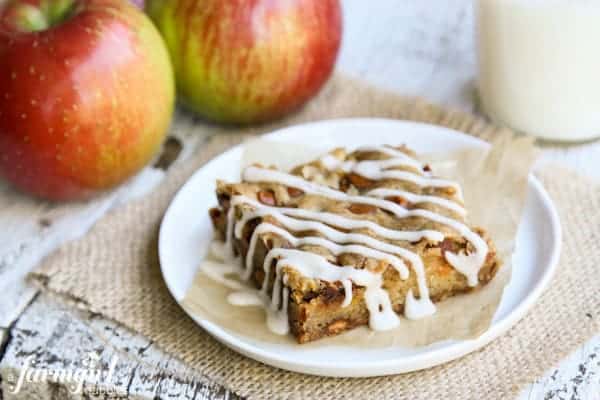 A slice of an Apple Bar with whole, fresh apples.